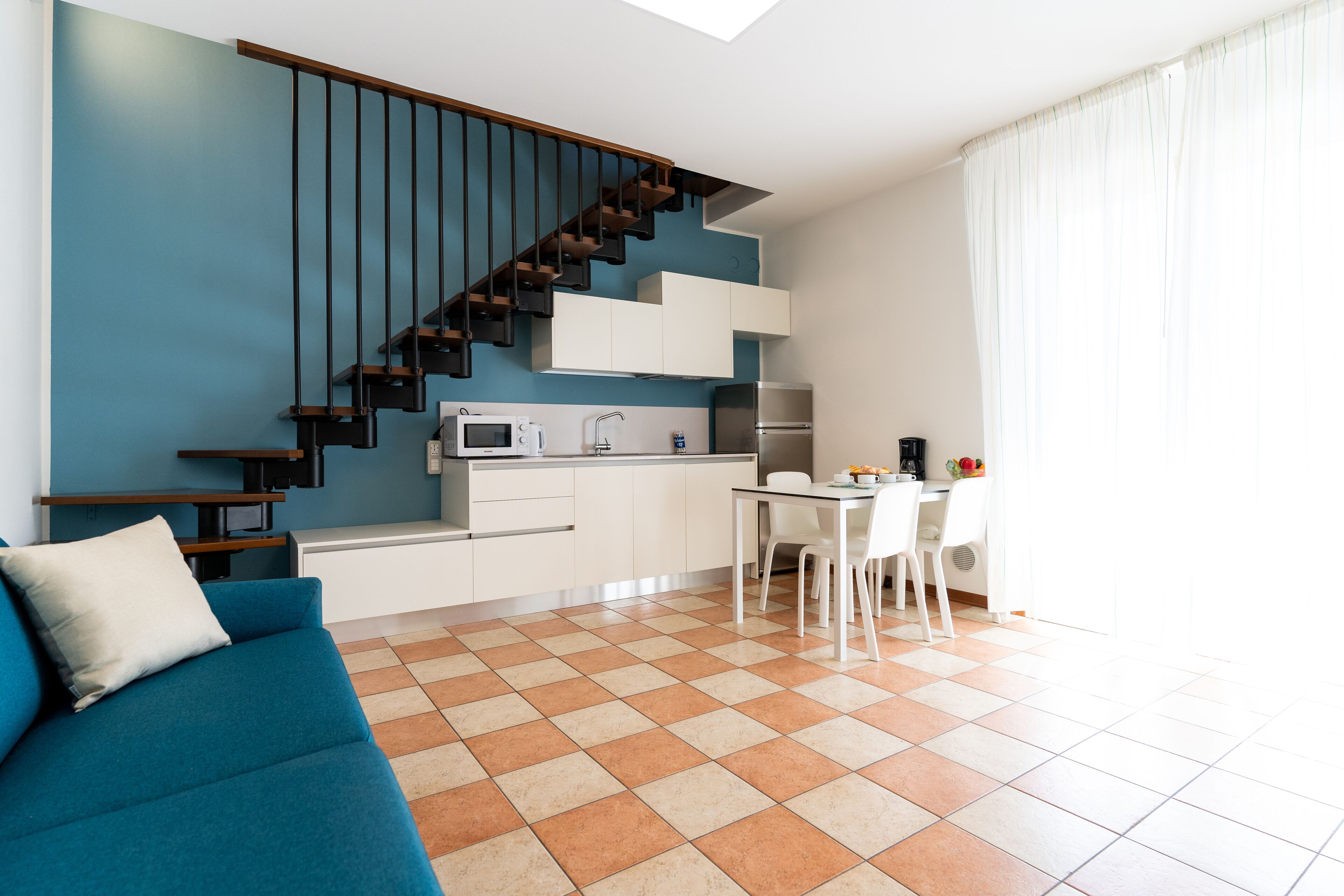 A modern kitchen with white cabinets, a stainless steel refrigerator, and a built-in oven.