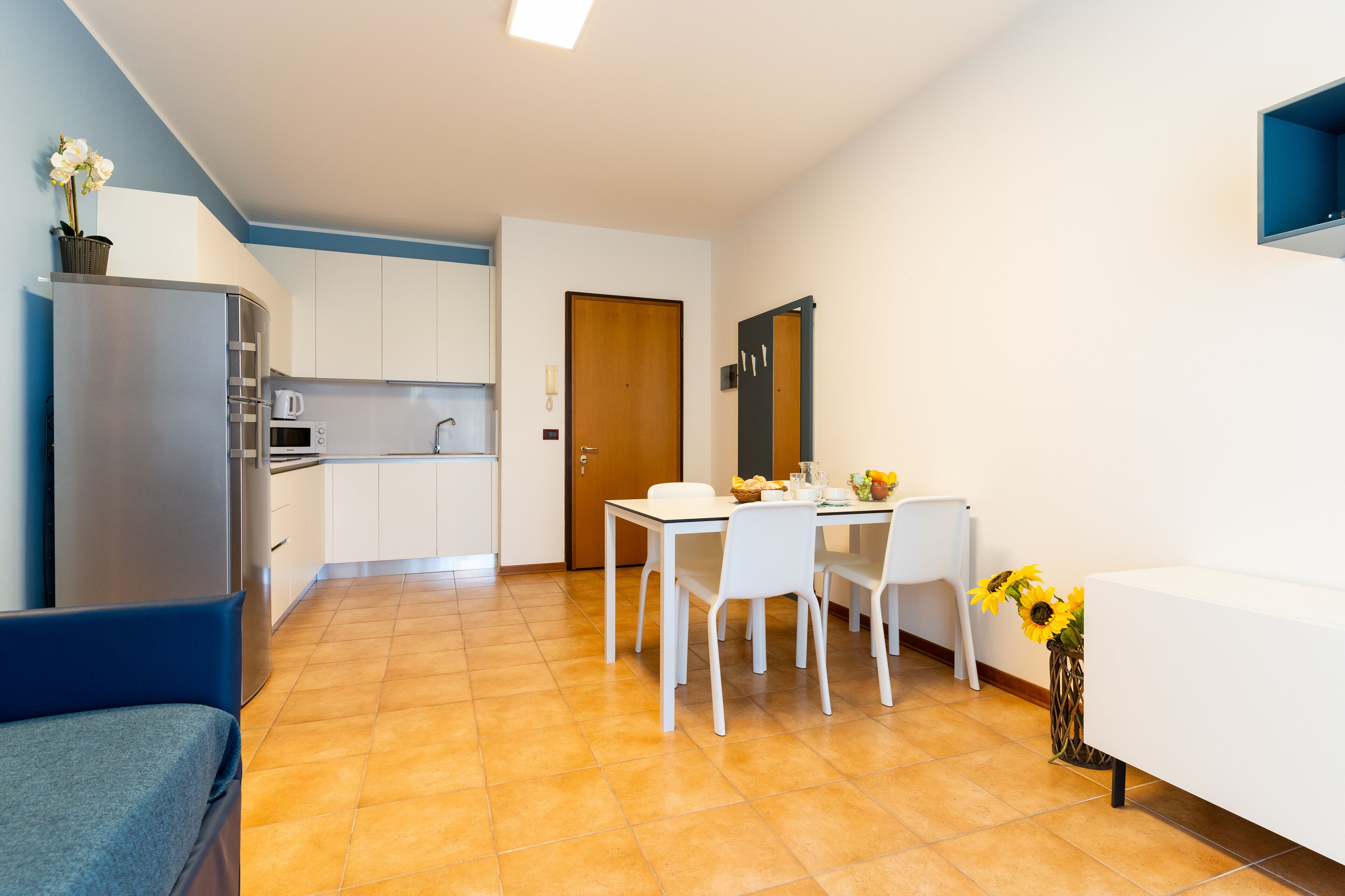 A compact kitchen with white cabinets, a built-in oven, and a dining area with a table and chairs.
