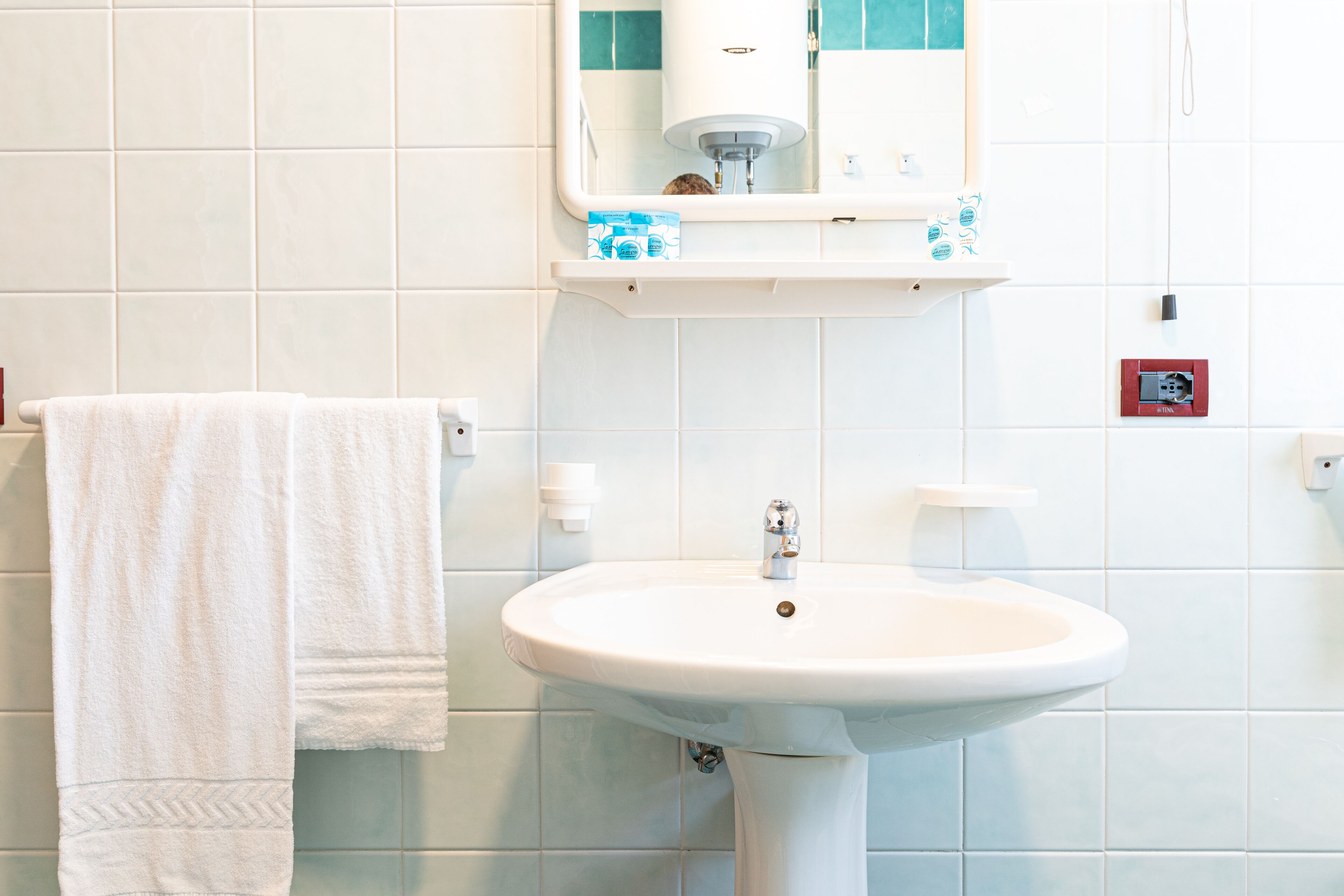 A bathroom with a white sink, a towel hanging on a rack, and a mirror above the sink.