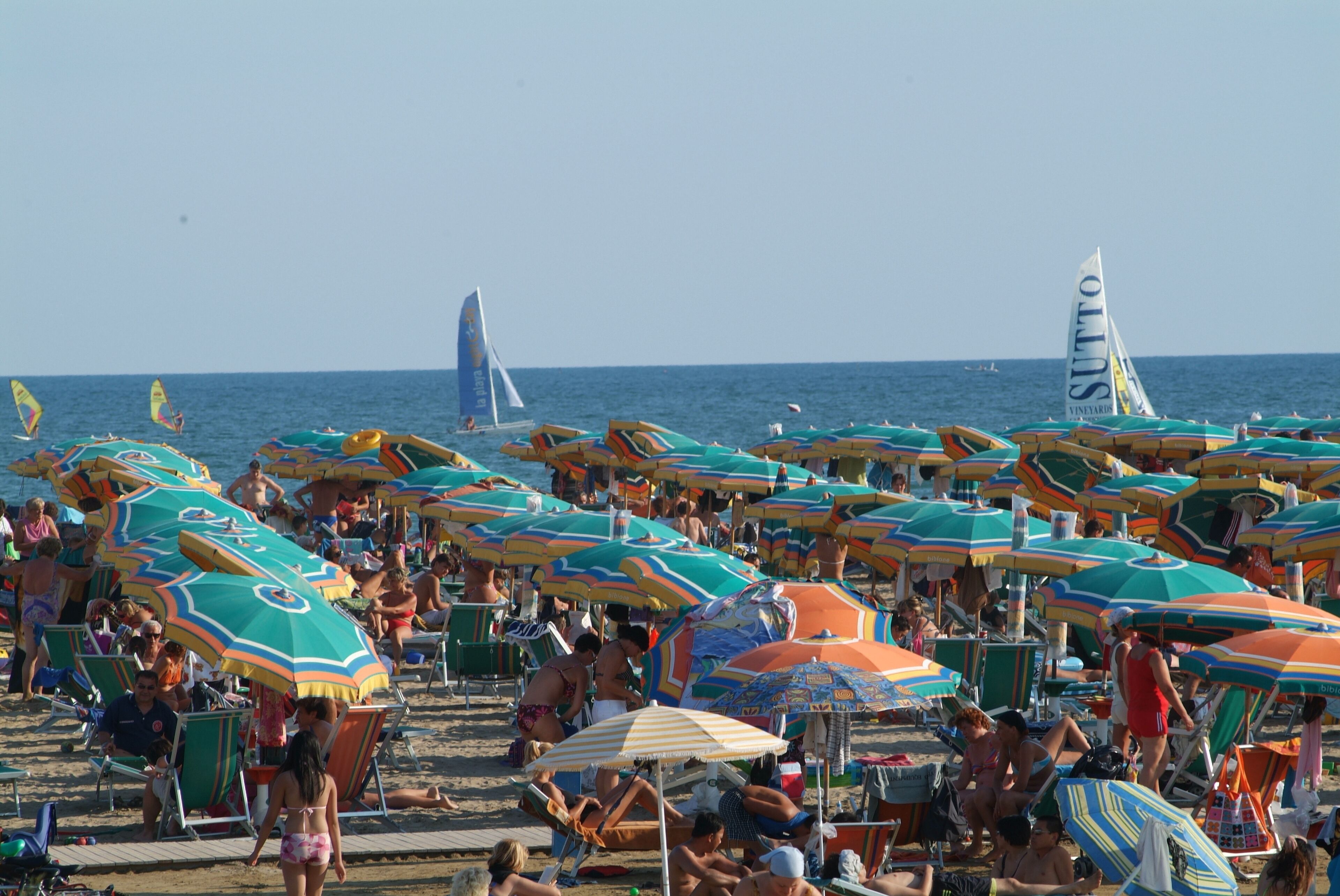 A crowded beach with numerous colorful umbrellas and beach chairs.