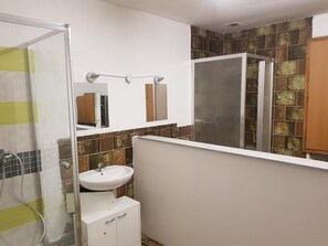 A bathroom with a shower, sink, and mirror.