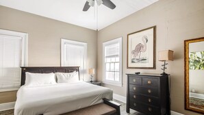 A bedroom with a bed, a bench, a dresser, a ceiling fan, and a framed picture on the wall. - Duval Dream Loft - On Duval street (Key West)