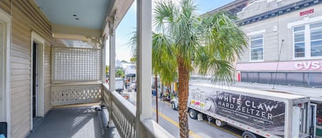 A balcony with a view of a street, a palm tree, and a CVS store.