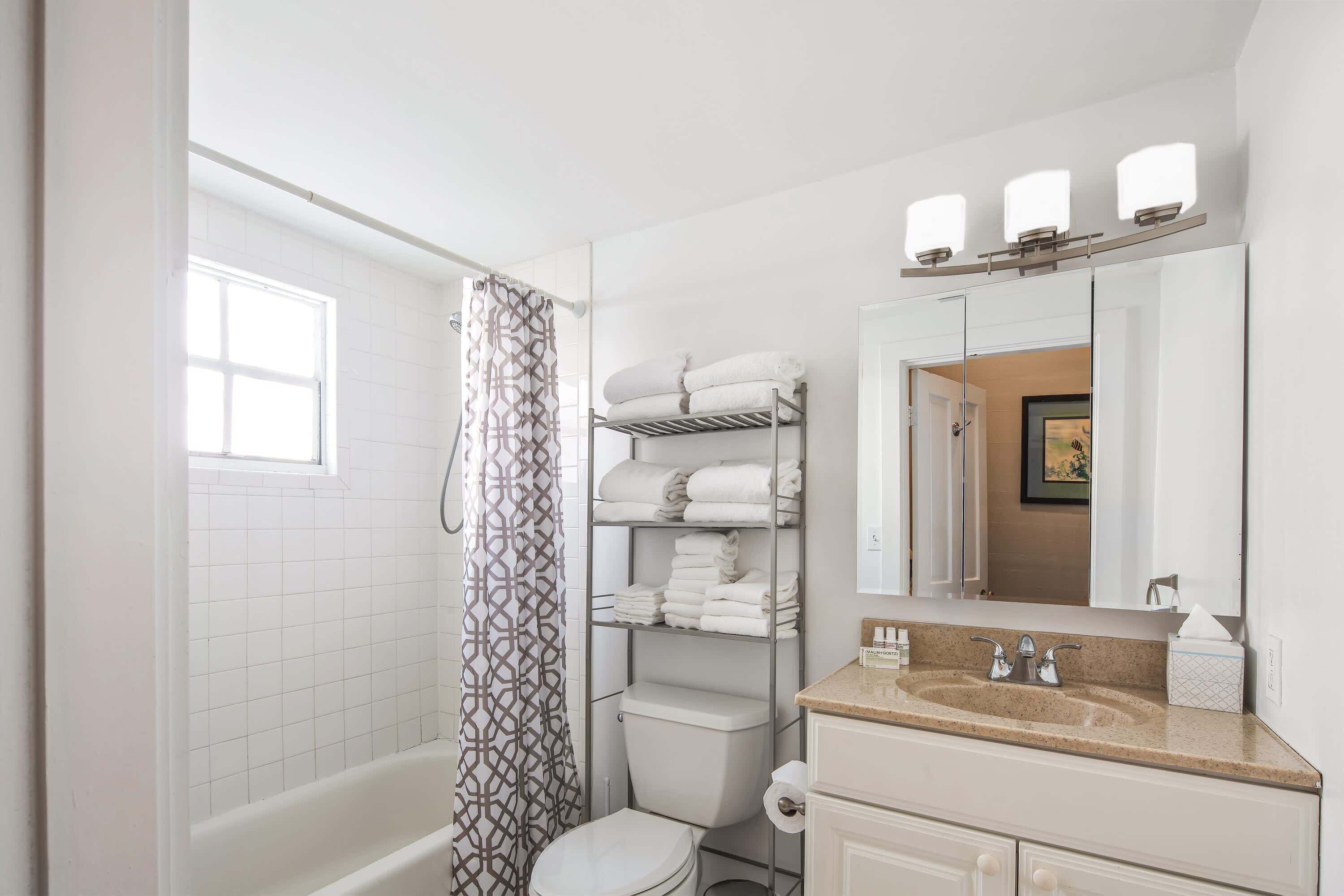 Ein Badezimmer mit Dusche, Toilette und Waschtisch inklusive Spiegel und Handtuchhalter.