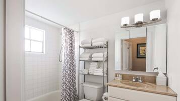 Ein Badezimmer mit Dusche, Toilette und Waschtisch inklusive Spiegel und Handtuchhalter.