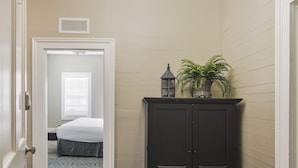 A hallway with a bed, a dark cabinet, and a potted plant.