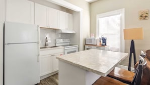 A kitchen with white cabinets, a refrigerator, microwave, and a coffee maker.