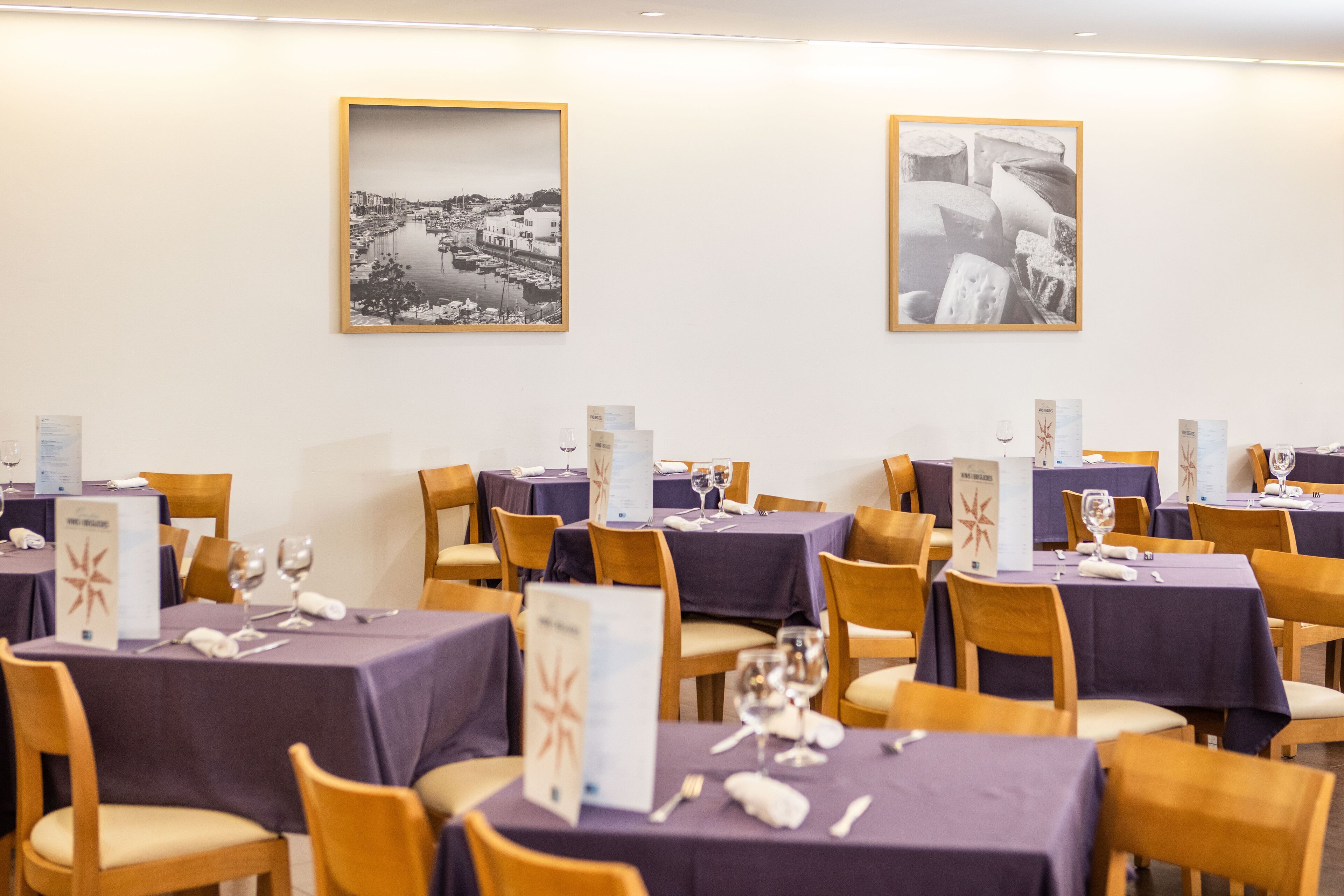 Un comedor con mesas dispuestas para recibir a los invitados, con vista a un paisaje urbano.