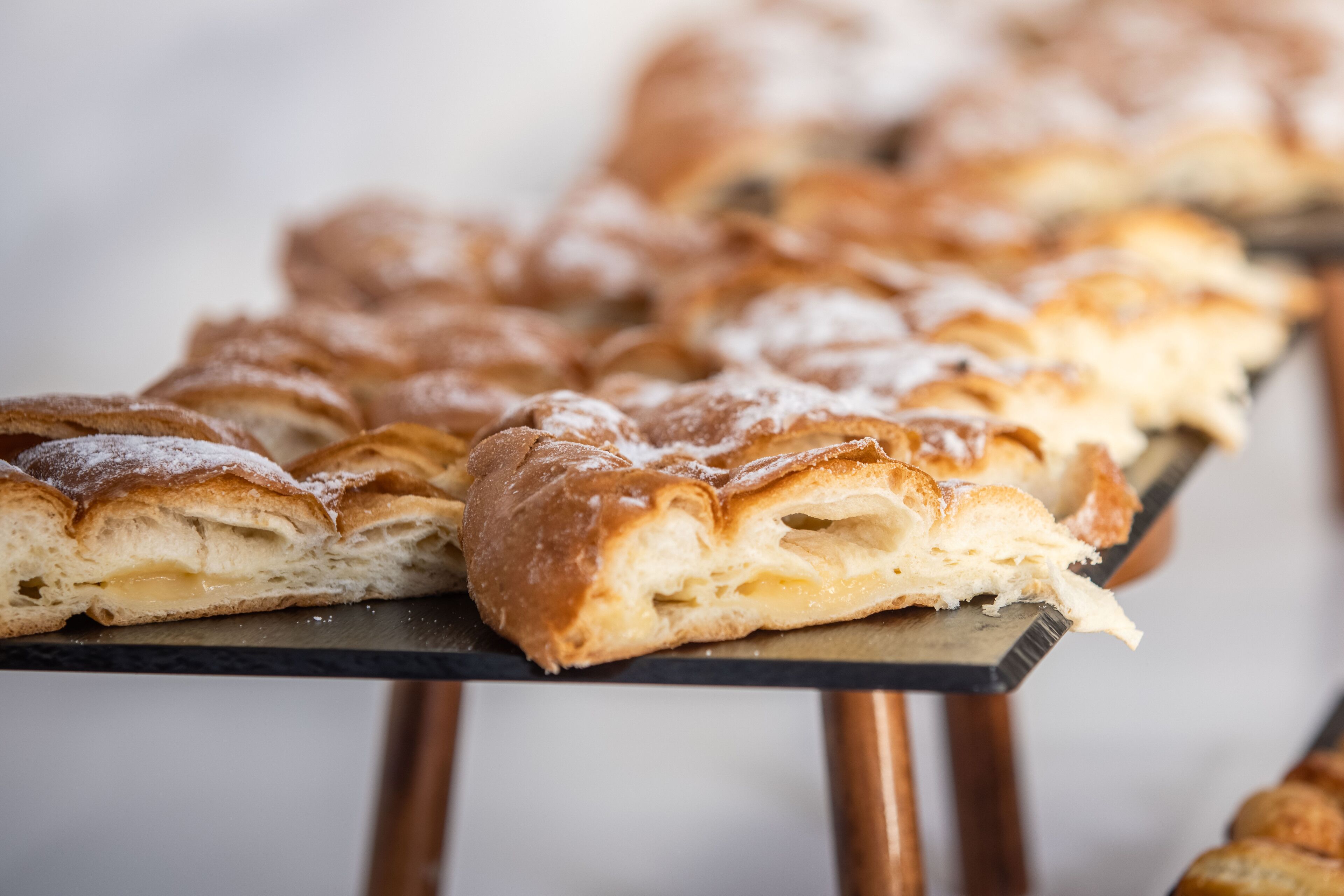 A tray of pastries with powdered sugar on a table.
