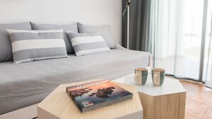 Ein modernes Wohnzimmer mit einem grauen Sofa, einem Holztisch und zwei Keramiktassen.