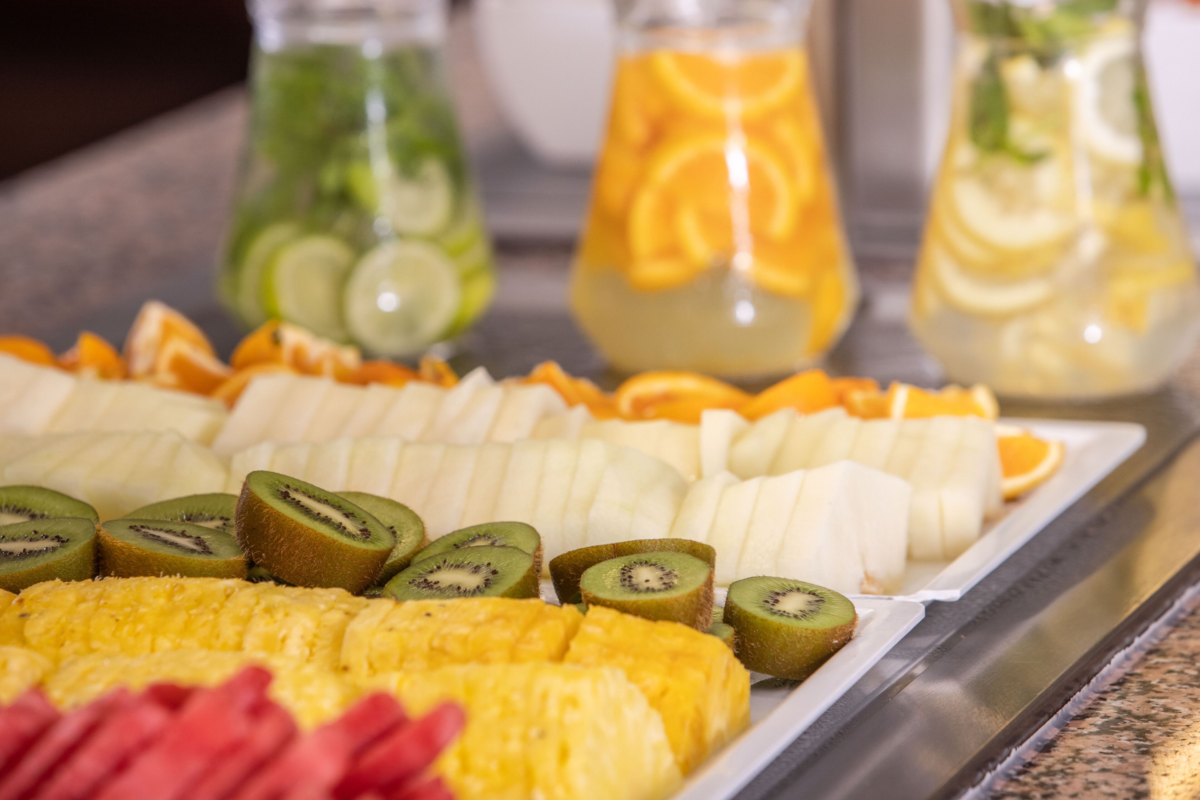 A buffet with various fruits and beverages.