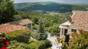 A villa with terracotta tiled roofs, surrounded by lush greenery and a view of a valley with buildings in the distance. - Villa Dub (Kotor)
