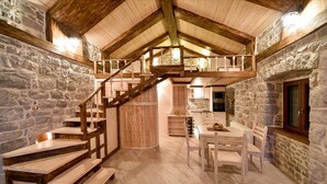 A rustic interior with a wooden staircase, stone walls, a dining area, and a kitchen. - Villa Dub (Kotor)