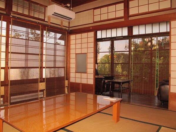 Ein traditioneller japanischer Raum mit Tatami-Boden, gleitenden Shoji-Schiebetüren und einem niedrigen Tisch mit Stühlen.