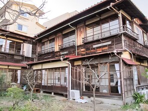 Un edificio de varios pisos con fachada de madera tradicional, ventanas grandes y un balcón.