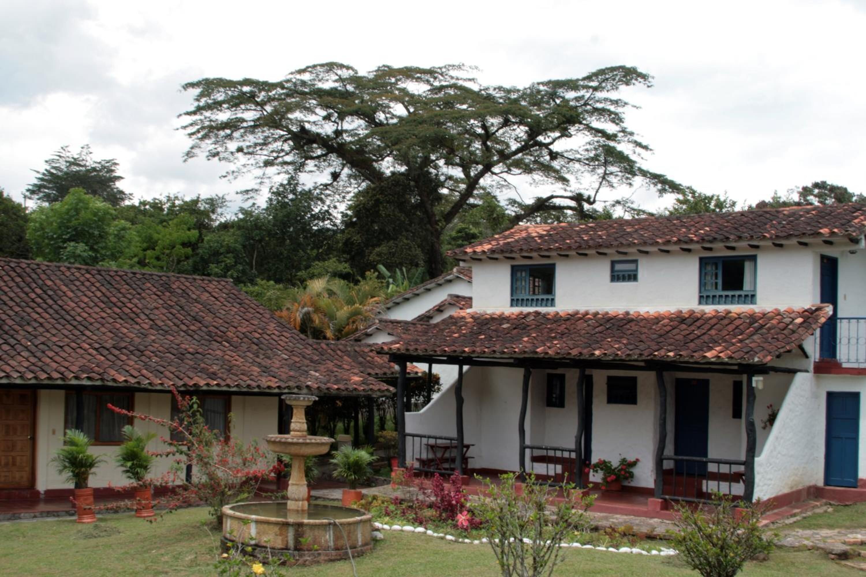 A traditional building with a tiled roof, a covered patio, and a small fountain in the garden.