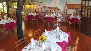 A restaurant with tables set for dining, a mural on the wall, and a tiled floor.