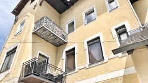 Un edificio de varios pisos con fachada amarilla, balcones con barandillas metálicas y múltiples ventanas.