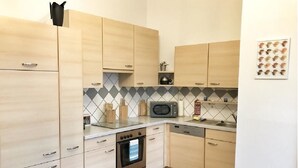 Una cocina compacta con armarios de madera, microondas, horno y lavavajillas.