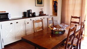 Un coin repas avec une table en bois, des chaises, une bouteille de vin et un bol décoratif.