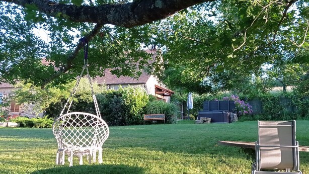 Un jardin avec une chaise suspendue, une table à manger et des chaises.