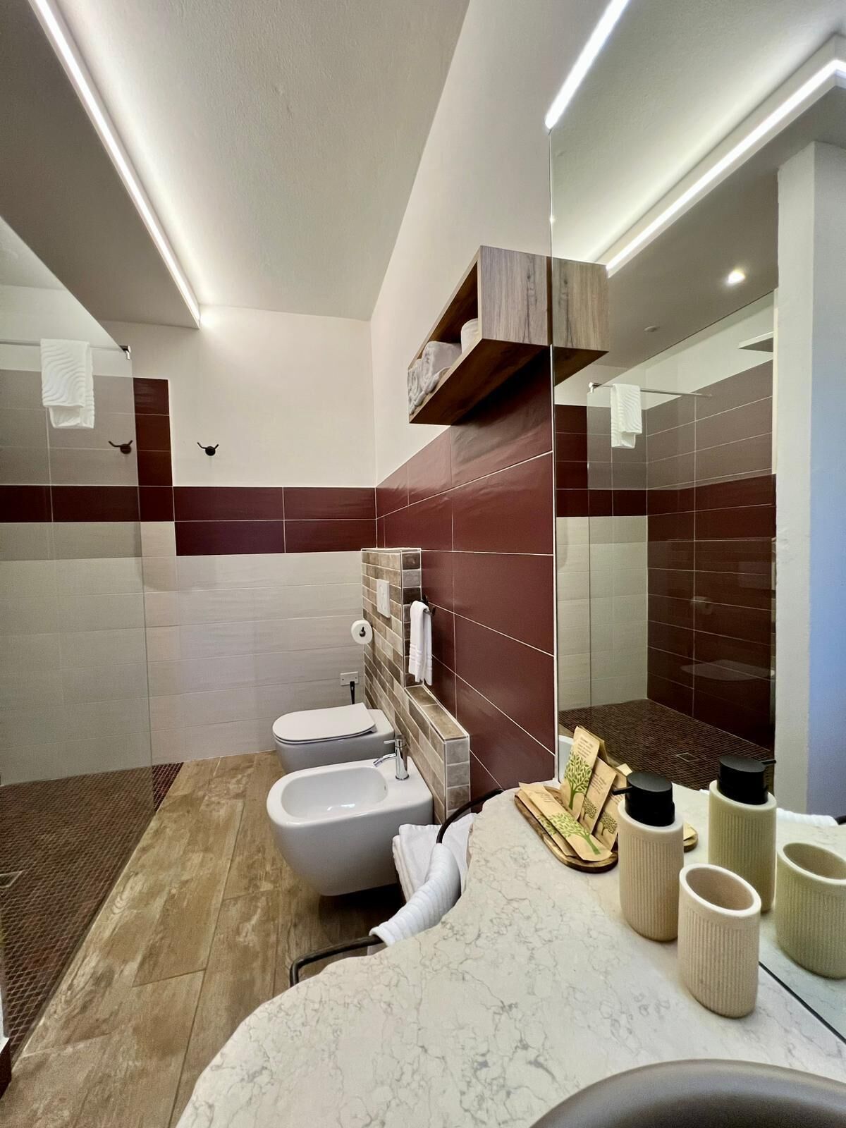 Ein modernes Badezimmer mit Waschtisch aus Marmor, einem Bidet, einer Toilette und einem großen Spiegel.