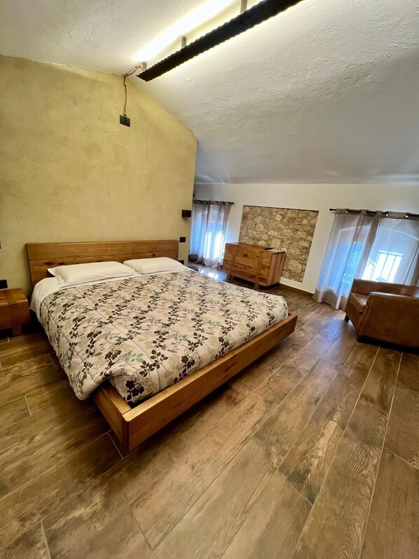 Un dormitorio amplio con una cama grande, cabecera de madera y una pared de acento de piedra.