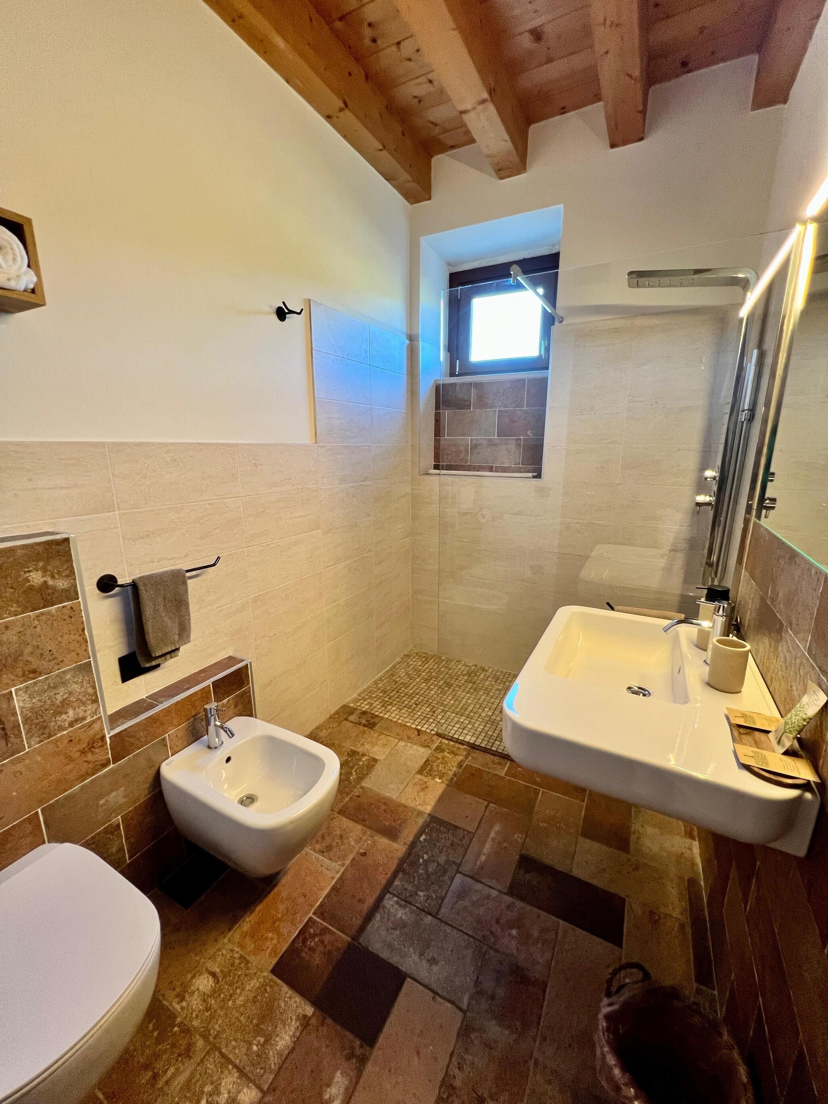 Un baño con bidé, lavamanos y ventana.