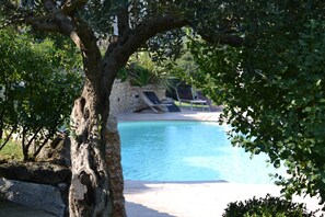 A pool area with lounge chairs and a stone wall in the background. - Agriturismo Tamellini (Soave)
