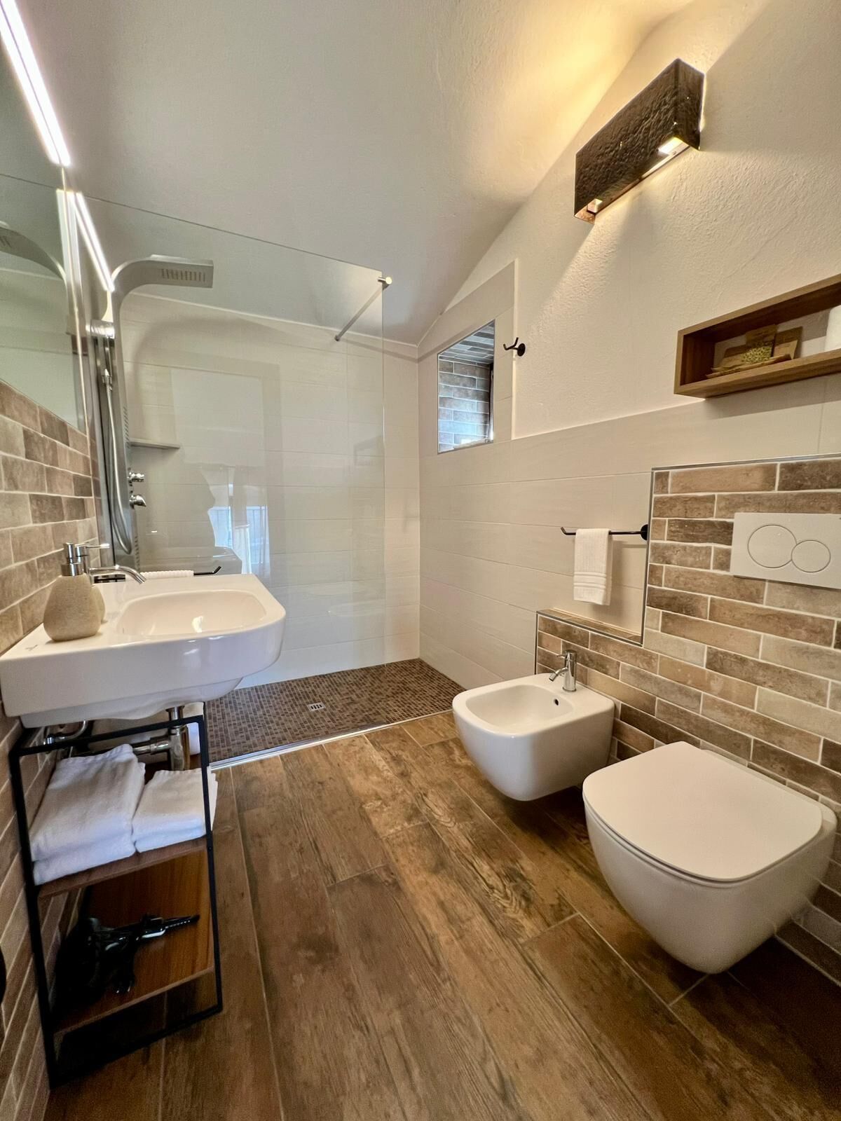 Une salle de bain moderne avec une douche à parois de verre, un lavabo sur pied, un bidet et des toilettes.