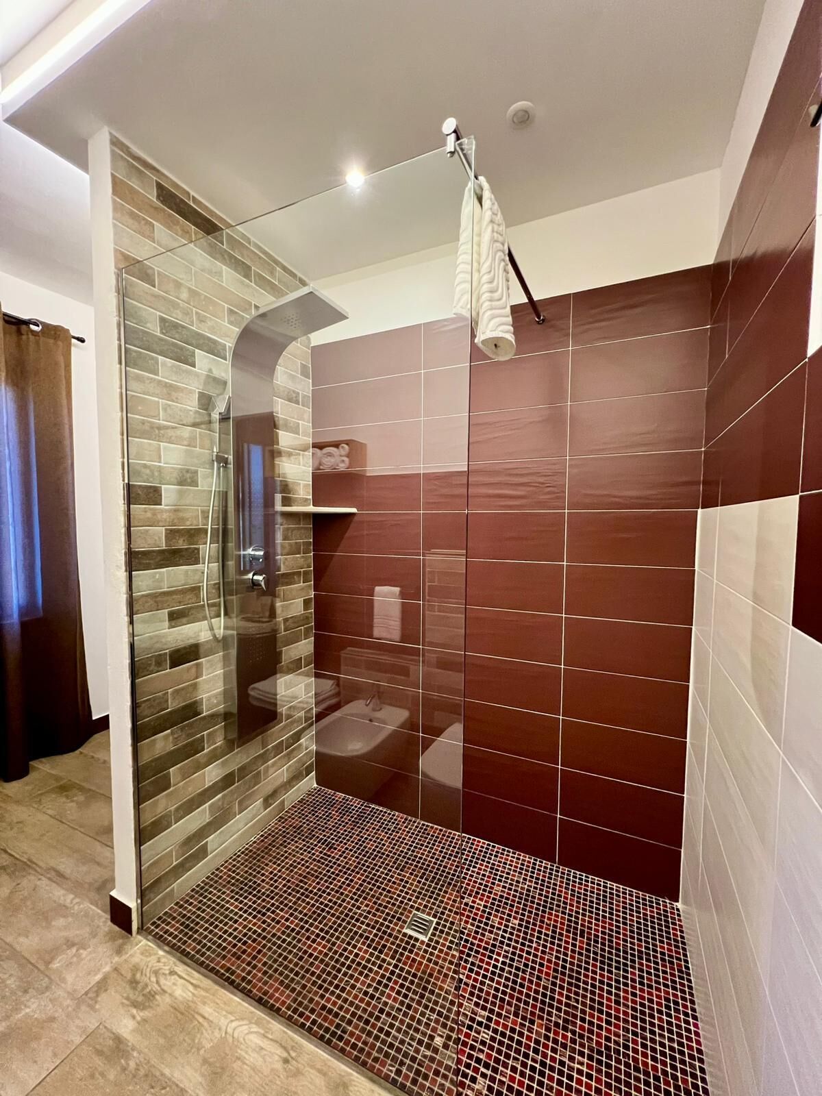 Un baño moderno con cabina de ducha de vidrio, lavamanos integrado y zona de ducha con azulejos.