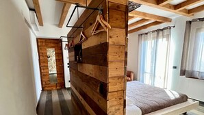 A bedroom with a wooden slat wall, a hanging clothes rack, a bed with a wooden frame, and a view of a cityscape through a window.
