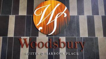 A sign for Woodsbury Suites at Harbour Place with a circular logo and the name in large letters.