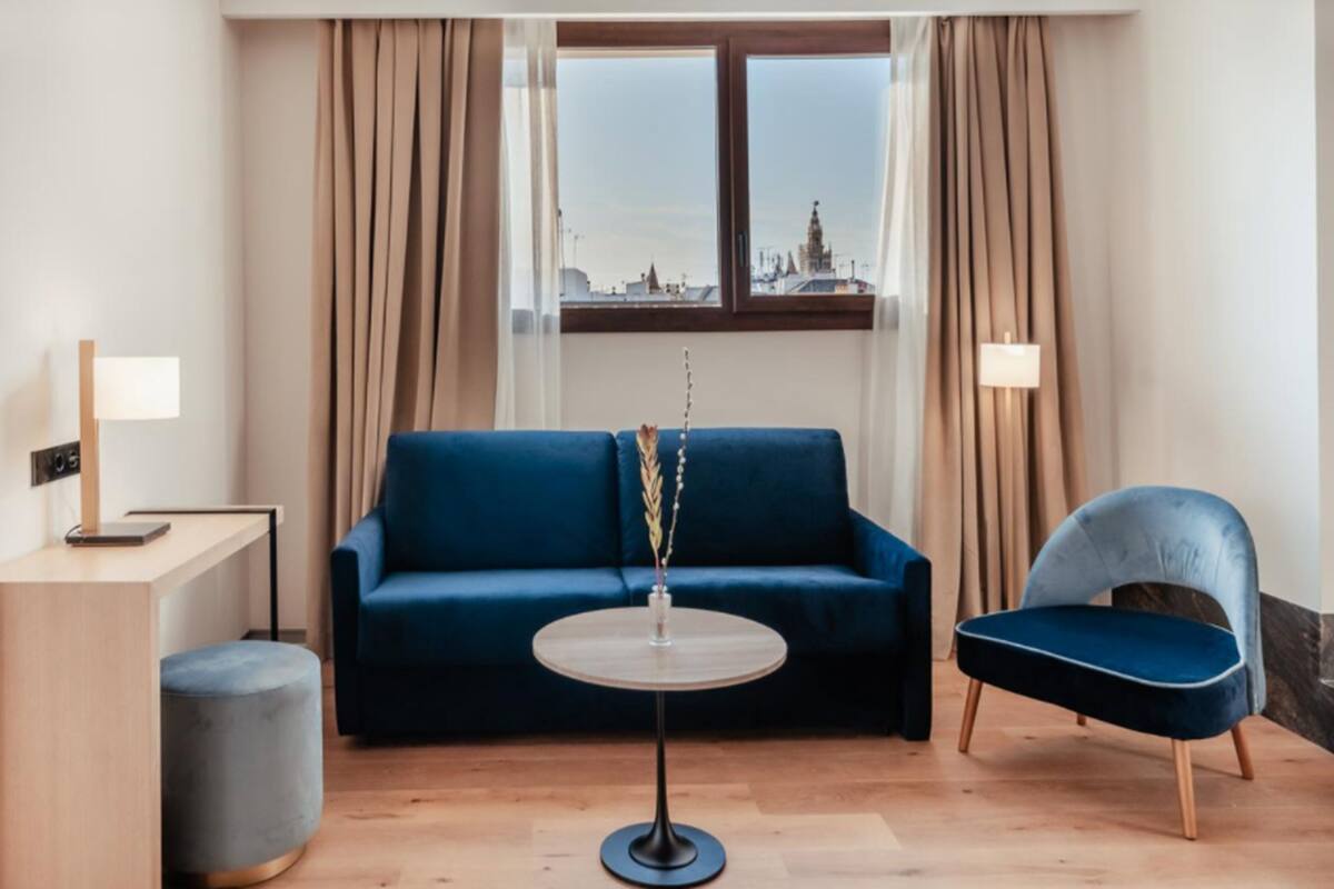 Una habitación moderna con un sofá azul, una mesa redonda, un reposapiés pequeño y una silla.