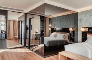 Una habitación de hotel moderna con una cama grande, mesitas de noche, un escritorio y un separador de vidrio.