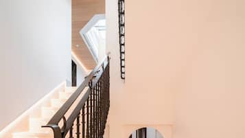 A staircase with ornate black railings leading to a living area with a patterned rug and a sofa.