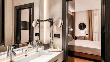 A hotel bathroom with a large mirror, a sink, and a hairdryer.