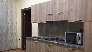 A kitchen with wooden cabinets, a stainless steel countertop, a gas stove, and a microwave. - B&B Duomo Pizzo ApartHotel (Pizzo)