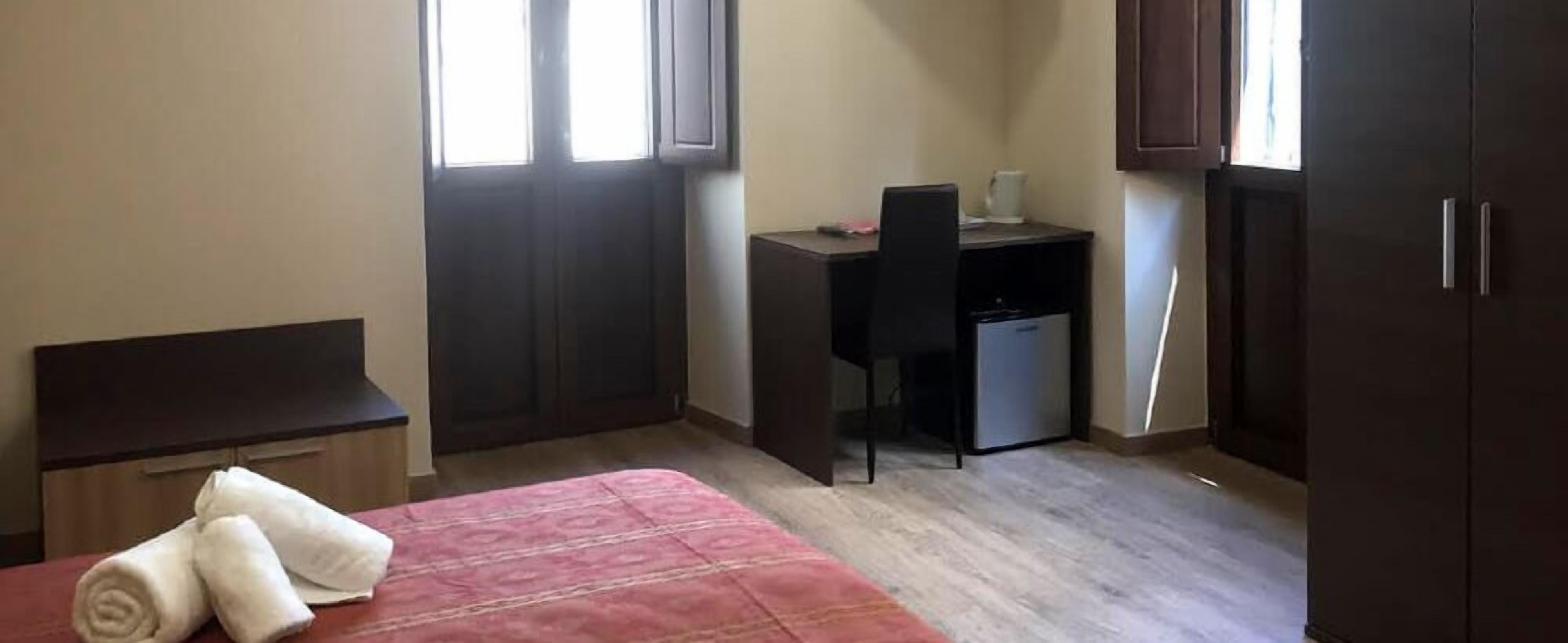 A small room with a bed, a desk, a chair, and a wardrobe.