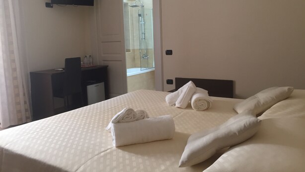 A hotel room with a bed, a desk, a TV, and a shower area. - B&B Duomo Pizzo ApartHotel (Pizzo)