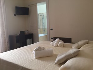 A hotel room with a bed, a desk, a TV, and a shower area. - B&B Duomo Pizzo ApartHotel (Pizzo)