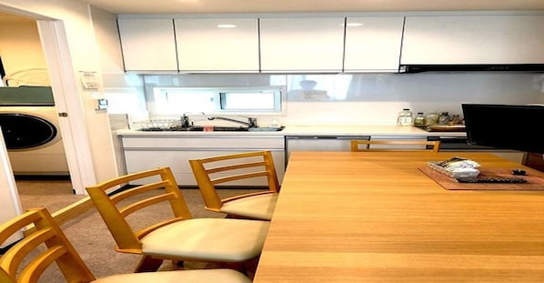 A compact kitchen with white cabinets, a sink, and a dining area with a wooden table and chairs.