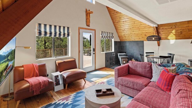 A spacious living area with a high ceiling, large windows, and a fireplace.