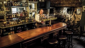 Un bar con mostrador de madera, varias botellas de licor y un bartender.