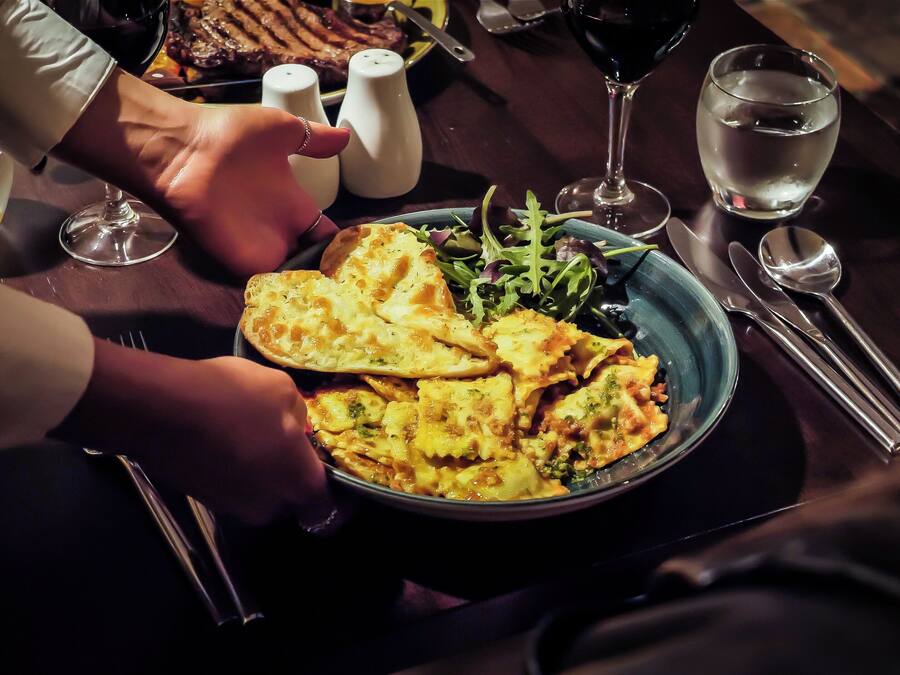Una mesa de comedor con un plato de comida, un vaso de agua y un salero.