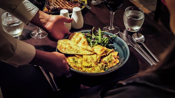A dining table with a plate of food, a glass of water, and a salt shaker. - Denvir's of Downpatrick (Downpatrick)