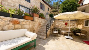 A stone building with a white bench, outdoor furniture, and potted plants. - Bucak Apart Hotel Göcek (Fethiye)