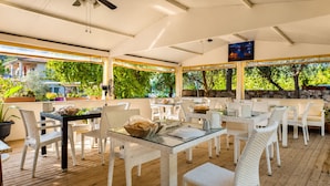 An outdoor patio with white wicker furniture, glass tables, and potted plants. - Bucak Apart Hotel Göcek (Fethiye)