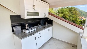 Una cocina compacta con armarios blancos, un lavamanos de acero inoxidable y un horno integrado.
