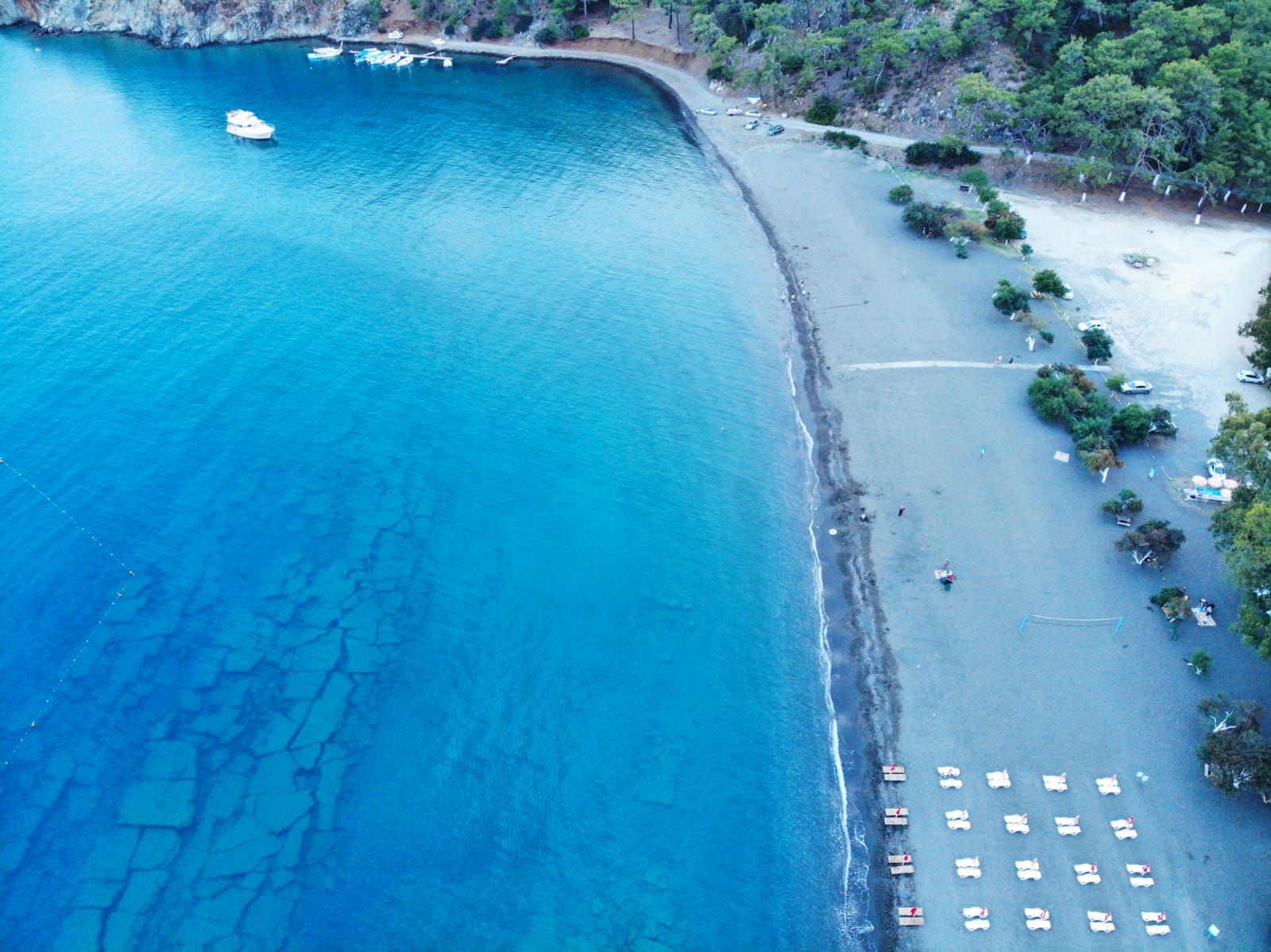 Vista aérea de una zona costera con playa, barcos y un acantilado.